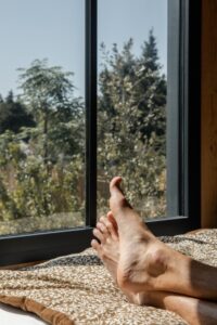 Pieds nus devant une baie vitrée dans une tiny house